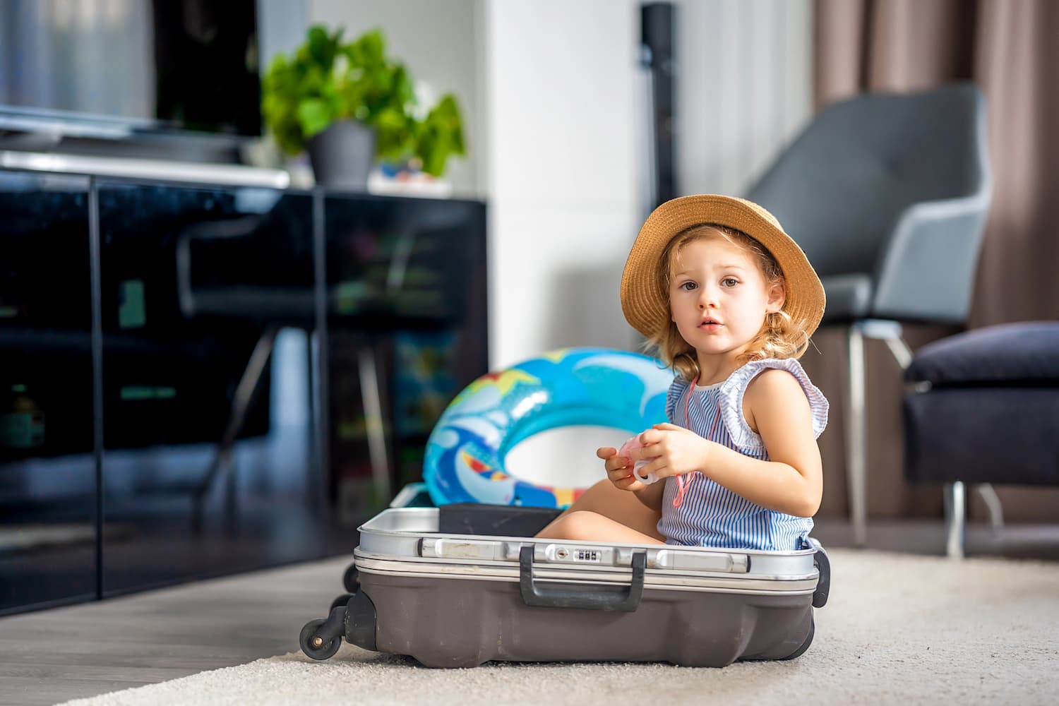 Little girl in holiday clothing sat in a suitcase